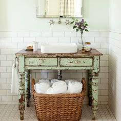 a bathroom sink sitting under a mirror next to a wooden table with baskets on it