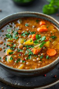 a bowl of soup with carrots, beans and parsley