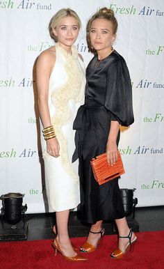 two women standing next to each other in front of a red carpet and white wall