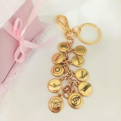 a gold keychain with six coins on it and a pink gift box in the background