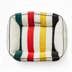 a dog bed made out of multicolored stripes with the name cooper on it