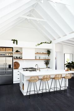 a white kitchen with lots of stools next to an oven and refrigerator freezer