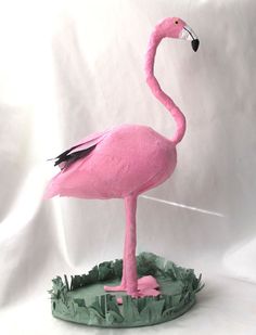 a pink flamingo standing on top of a green base