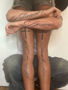 two people sitting on the ground with their legs crossed and tattoos written on each leg