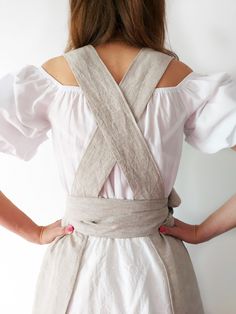 the back of a woman's white dress with cross - over straps and buttons