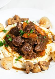 a white plate topped with mashed potatoes and meat