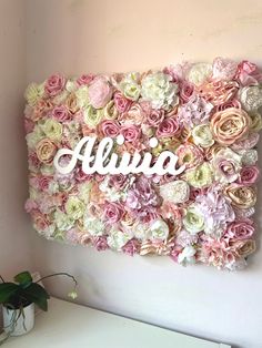 a flower wall with the word aluna written on it in white and pink flowers