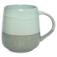 a green and white coffee mug with speckles on the outside, sitting in front of a white background