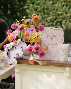 a table topped with lots of flowers next to a sign