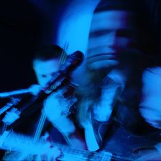 two men are playing guitars in the dark