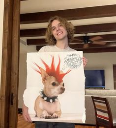 a person holding up a poster with a dog wearing a red mohawk on it's head