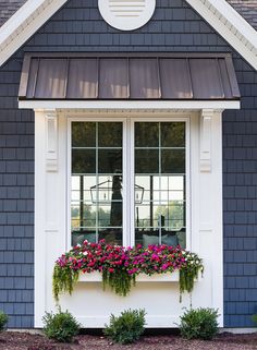 a window box with flowers in it on the side of a blue and white house