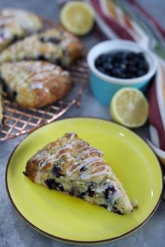 a slice of blueberry scones on a yellow plate next to some lemons