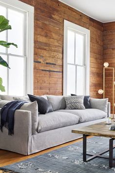 a living room filled with furniture and wooden wall paneled in wood planks on the walls