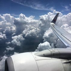 the wing of an airplane as seen from above in the sky with clouds and blue sky