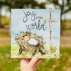 a hand holding up a card that says joy to the world with a cross in the background