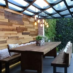 an outdoor dining area with wood paneling and lights hanging from the ceiling above it