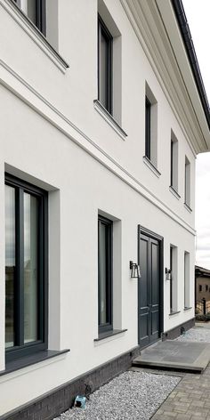 a white building with black windows and some gravel