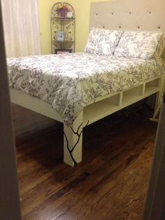 a bed sitting on top of a hard wood floor next to a wall mounted shelf