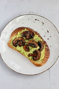 an avocado toast with mushrooms on it is served on a white and gold plate