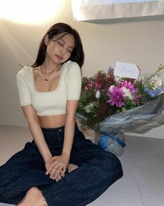 a woman sitting on the floor next to flowers