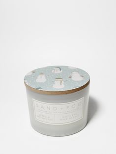 a candle that is sitting on top of a white surface with clouds in the background