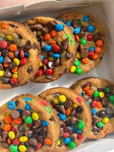 several cookies with m & m and chocolate chips in a white box on the table