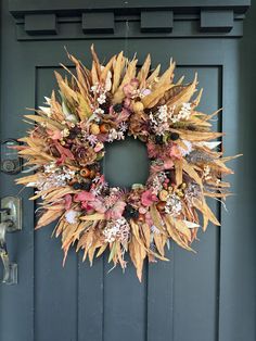 a wreath on the front door of a house decorated with dried flowers and foliages