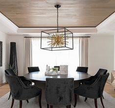 a dining room table with black chairs and a chandelier hanging from the ceiling