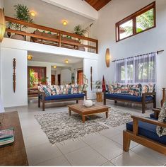 a living room with blue couches and wooden tables in front of the windows on the second floor