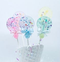 there are three lollipops in the bag with ribbons on them and confetti