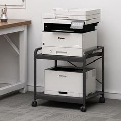 a stack of printer's sitting on top of each other in front of a desk