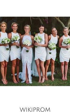 a group of women standing next to each other in white dresses holding bouquets and flowers