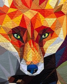 a close up of a quilt with a fox on it's face and green eyes