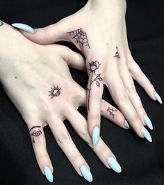 two woman's hands with tattoos on their fingers, one has an eye and the other has a spider web