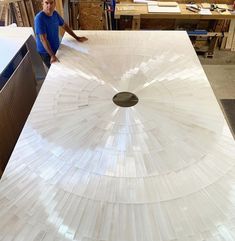 a man standing next to a large white piece of wood with a hole in it