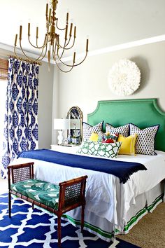 a bedroom with blue and white decor, chandelier, and green headboard