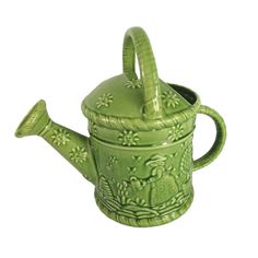 a green teapot with a handle and flower design on it's side, sitting in front of a white background