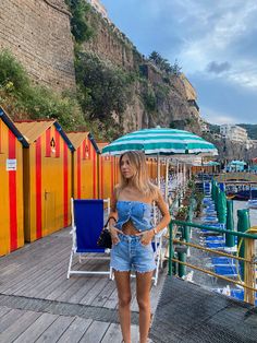 a woman standing on a dock next to colorful beach huts