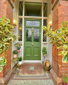 a green front door with potted plants on either side