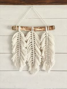 three white feathers hanging on a wall