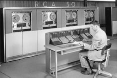 a man sitting at a desk in front of some machines