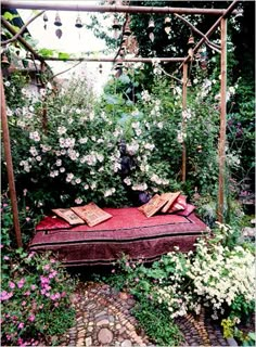 an outdoor bed surrounded by flowers and greenery