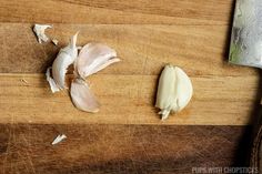 two pieces of garlic sitting on top of a wooden cutting board next to a knife