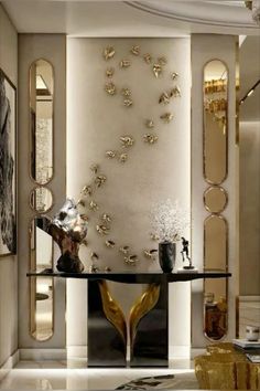 an elegant living room with gold accents and mirrors on the wall, along with a black table