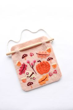 a pink bag with an orange flower and mushrooms on it, hanging from a string