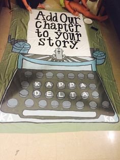 two people sitting on the floor with a cake made to look like an old fashioned typewriter