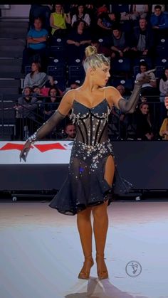 a woman in a black and silver dress standing on top of a ice skating rink