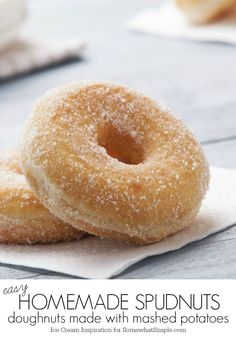 two sugar covered donuts sitting on top of a napkin