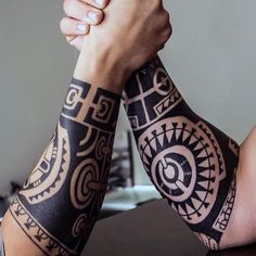 two hands holding each other with tattoos on them